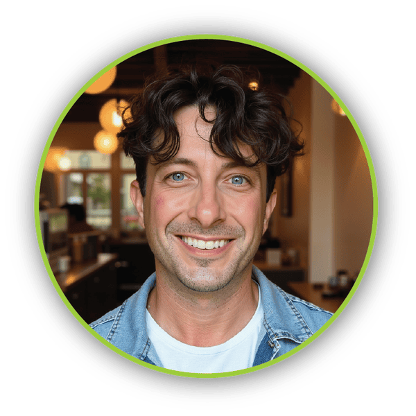 Lee_Heike Lee Heike – Smiling man with curly hair in a denim jacket, standing in a cozy coffee shop.